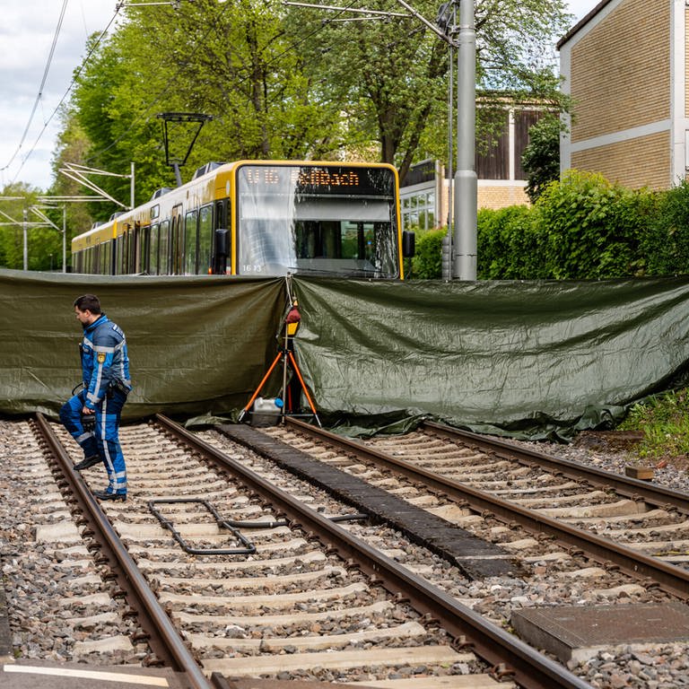 Eine Stadtbahn steht an einer Haltestelle in Stuttgart. Die tödliche Unfallstelle wurde von den Rettungskräften mit einer grünen Plane abgeschirmt.  (Foto: 7aktuell.de)