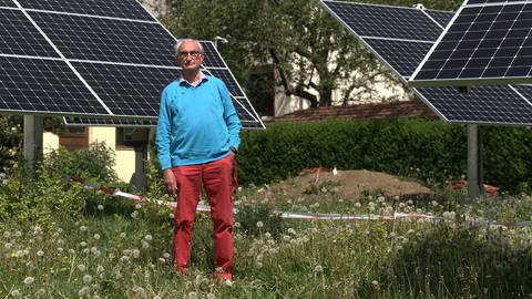 Willi Kemmler steht im Garten seiner Mietshäuser in Gomaringen (Kreis Tübingen). Um ihn herum ist ein Teil der Solaranlagen zu sehen, für die er seit fast einem Jahr keine Genehmigung bekommt. (Foto: SWR)